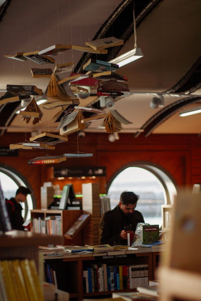 Interior view of a bookstore featuring creative book art and a man reading, creating a cozy atmosphere.